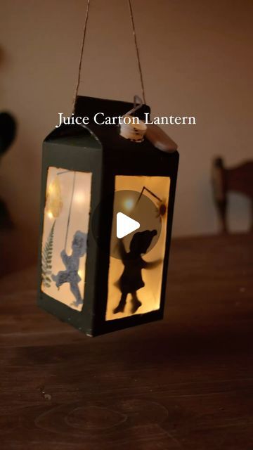 a lantern that is hanging from a string on a table with the silhouettes of two people