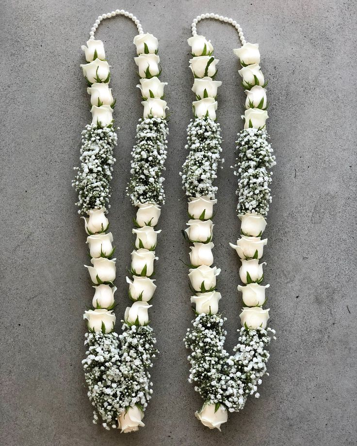 three white roses and baby's breath flowers are arranged on the floor with beads