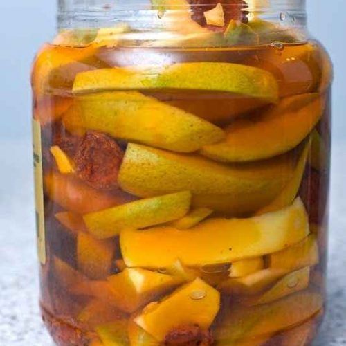 a glass jar filled with sliced fruit on top of a table