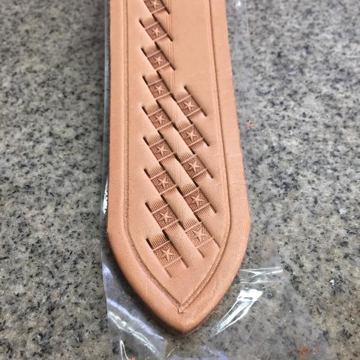 a close up of a piece of brown leather on a counter top with plastic wrapping around it