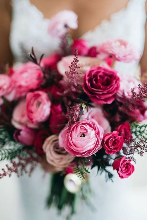 a bride holding a bouquet of pink and red flowers