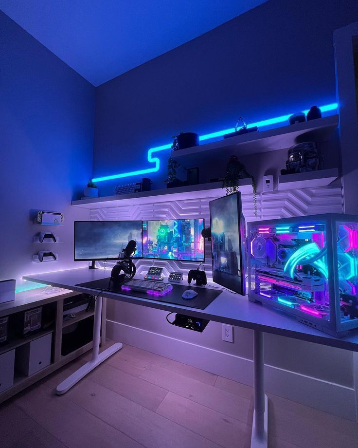 a computer desk with two monitors on top of it in front of a blue light