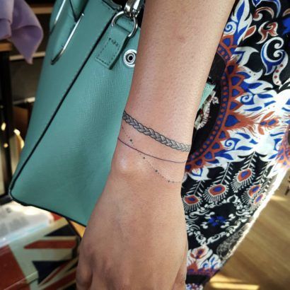 a woman with a wrist tattoo holding a green purse and wearing a chain around her arm