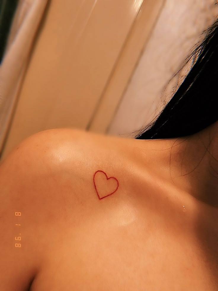 a woman with a red heart tattoo on her shoulder