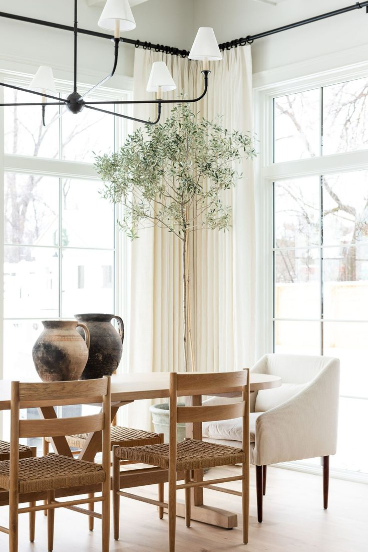 a dining room table with chairs and a vase on the table in front of it