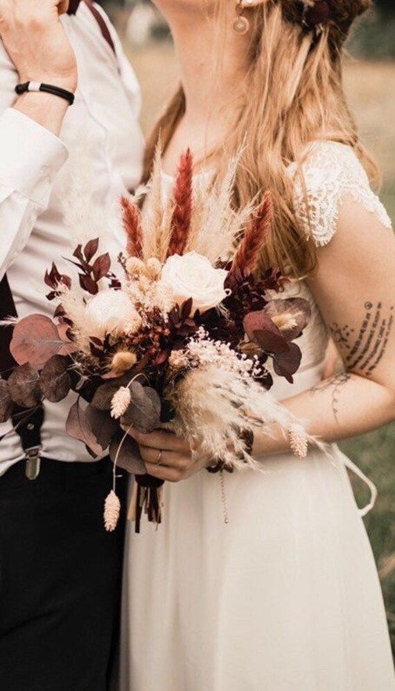 a bride and groom kissing in front of an outdoor setting with greenery on the grass