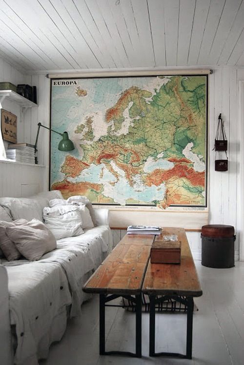 a living room filled with furniture and a large map on the wall above it's coffee table