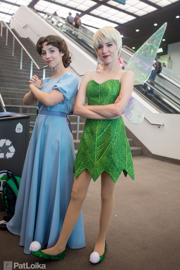 two women dressed as tinkerbells standing next to each other in front of an escalator