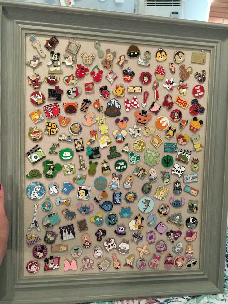 a person holding up a framed artwork with many different pins on the front and back of it