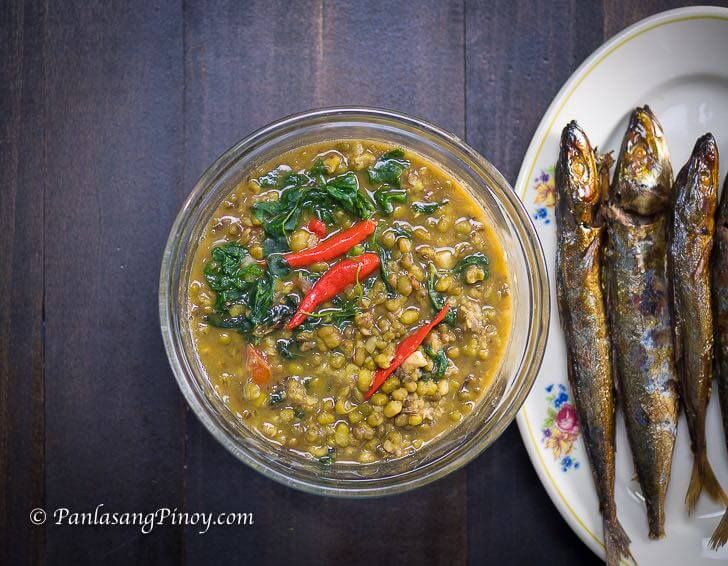 an image of some fish on a plate next to another dish with beans and spinach