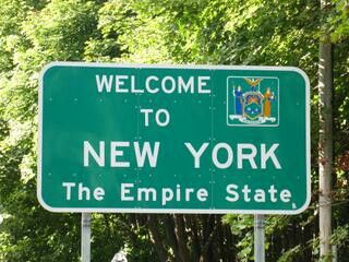 a welcome sign to new york, the empire state is posted in front of some trees