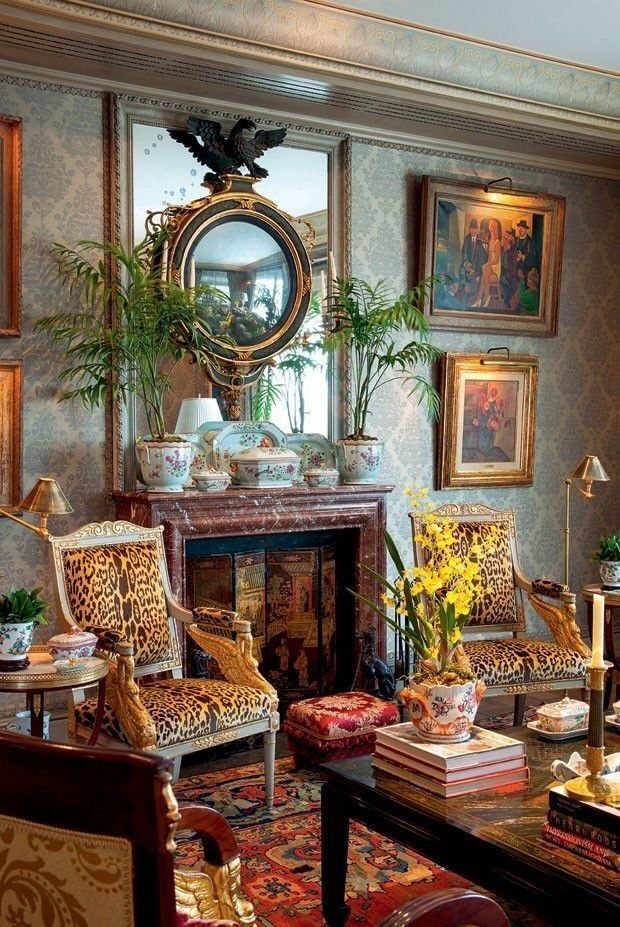 a living room filled with lots of furniture and paintings on the wall next to a fire place