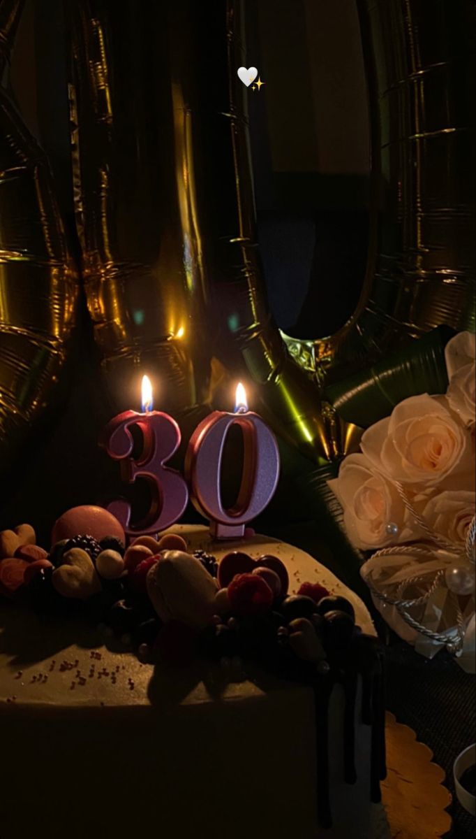 a birthday cake with candles and flowers on it in front of two mirrors that say 30