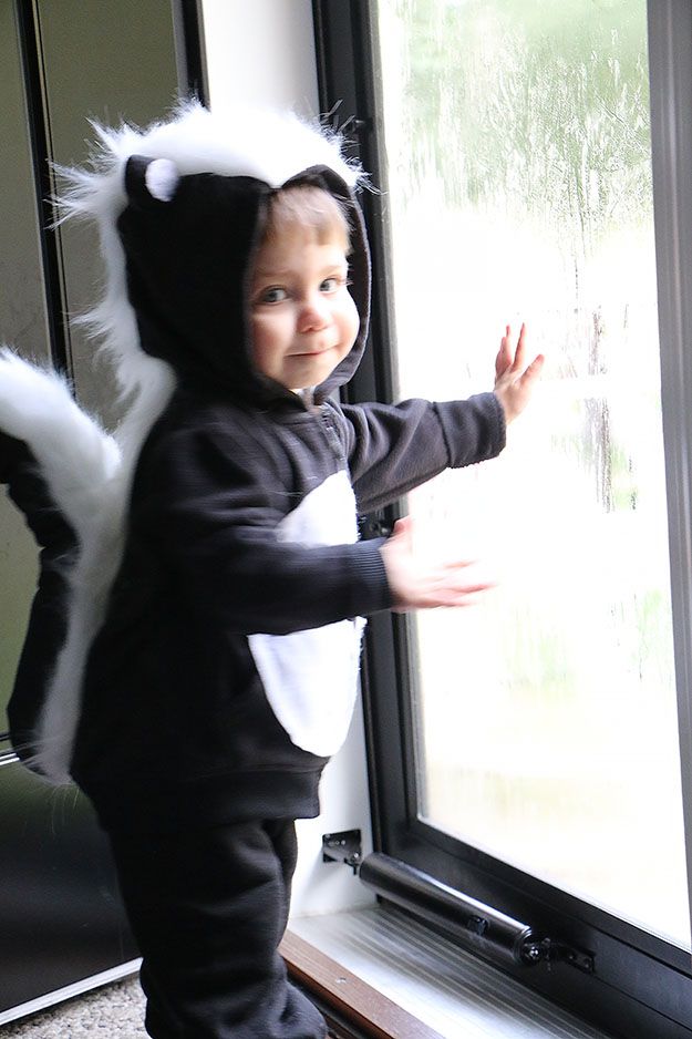 a small child in a costume standing next to a window