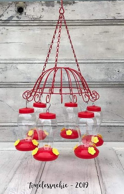 a red birdcage with yellow flowers hanging from it's sides on a wooden table