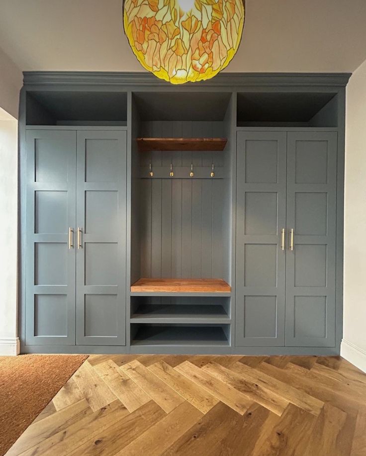 an empty room with wooden flooring and blue cupboards on either side of the wall