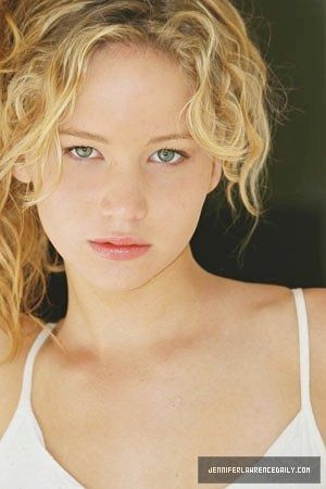 a close up of a woman with blonde hair and blue eyes looking at the camera