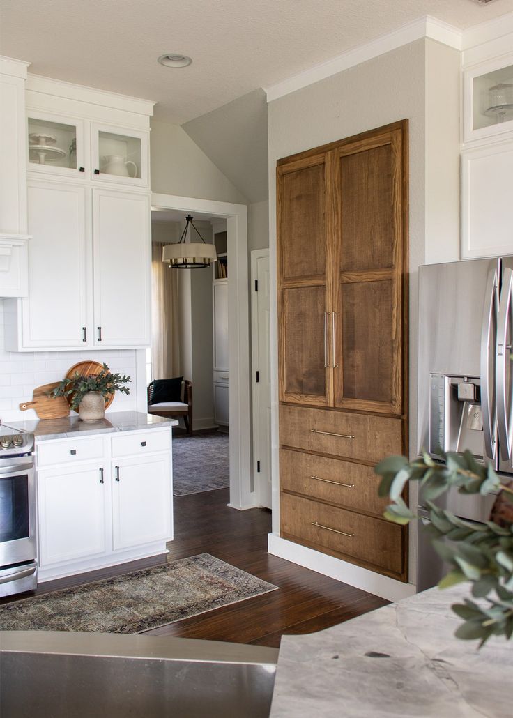 a kitchen with white cabinets and stainless steel appliances in the center, along with an open door leading to another room