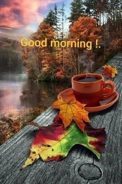 a cup of coffee sitting on top of a wooden table next to a fall leaf