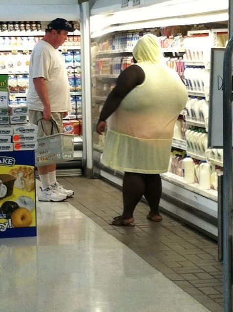 two people in a grocery store looking at items on the shelves and one person is wearing a yellow dress