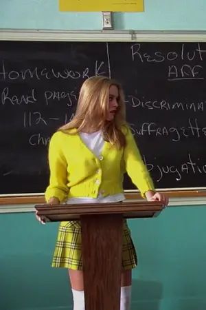 a woman standing at a podium in front of a blackboard