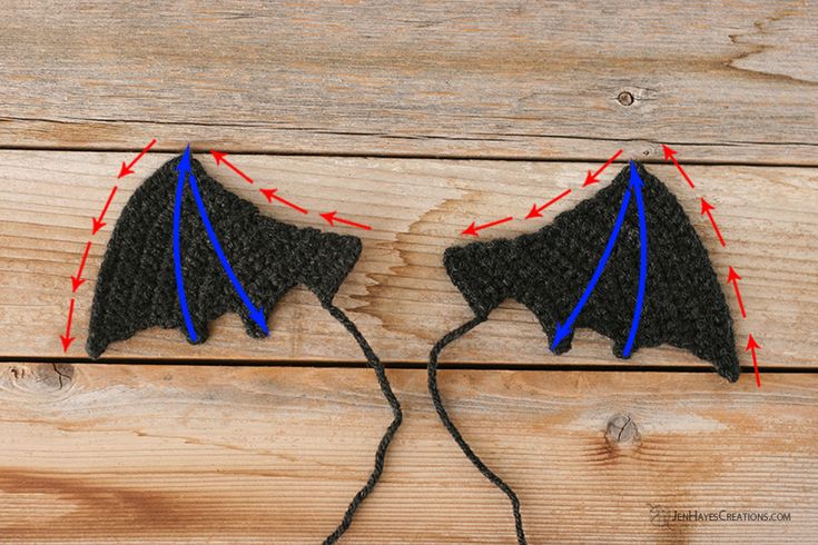 two black and blue kites are connected to each other on a wooden surface with red arrows pointing towards them