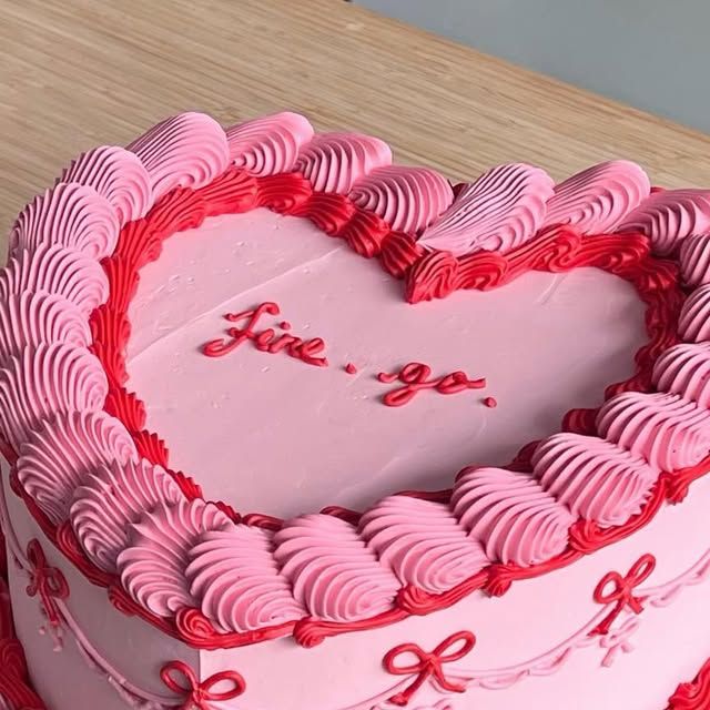 a pink heart shaped cake on a wooden table