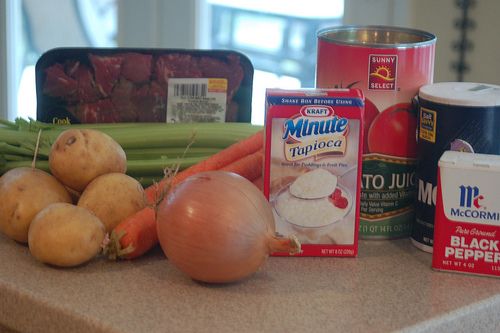 some vegetables are sitting on a counter next to cans of milk and other food items