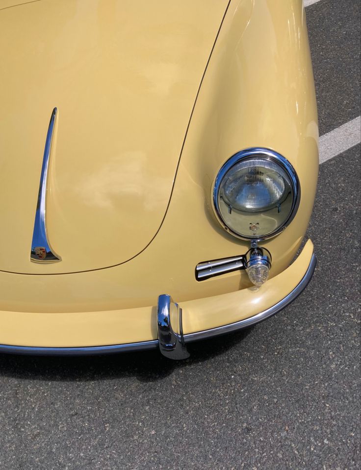 the front end of an old yellow sports car