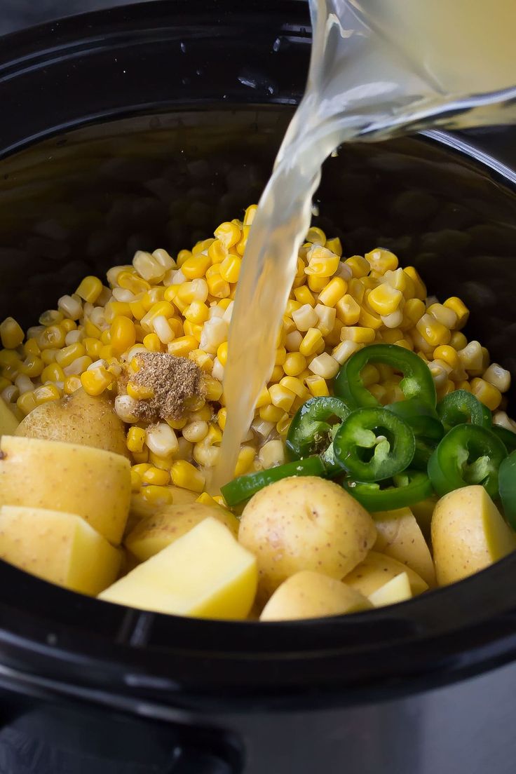 corn and potatoes being poured into a slow cooker