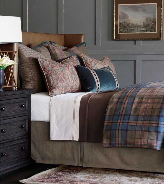 a bed with many pillows on top of it and a painting above the headboard