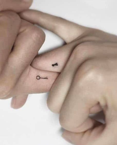 two hands holding each other with small tattoos on their fingers