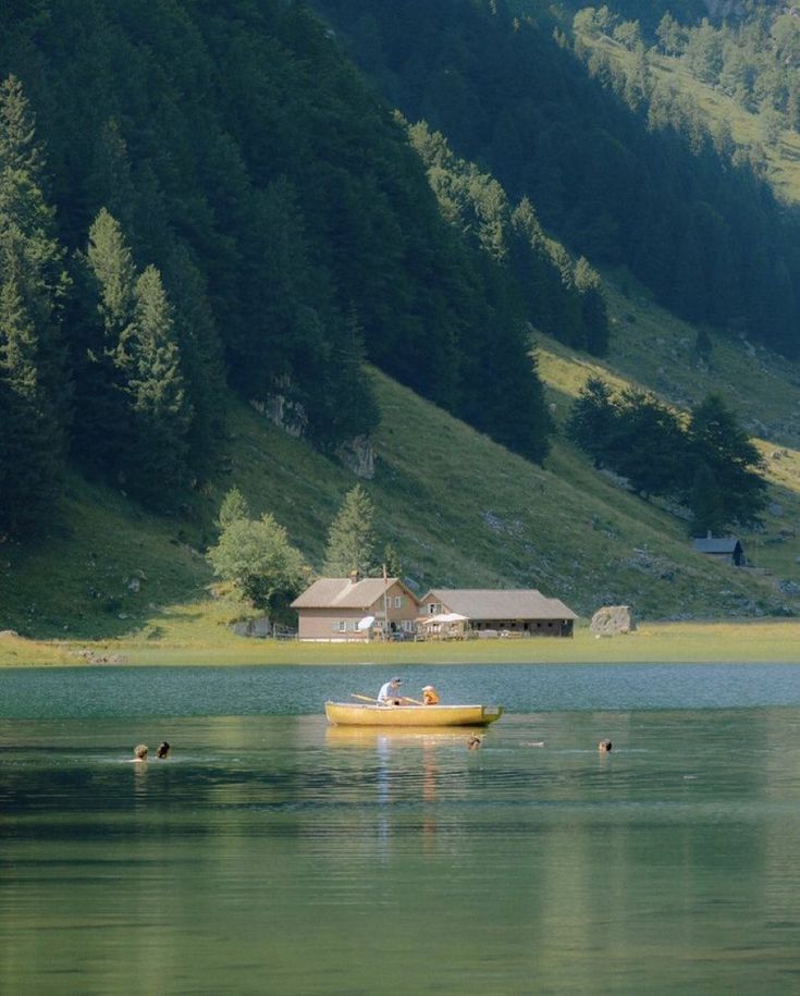 a small yellow boat floating on top of a lake next to a lush green hillside