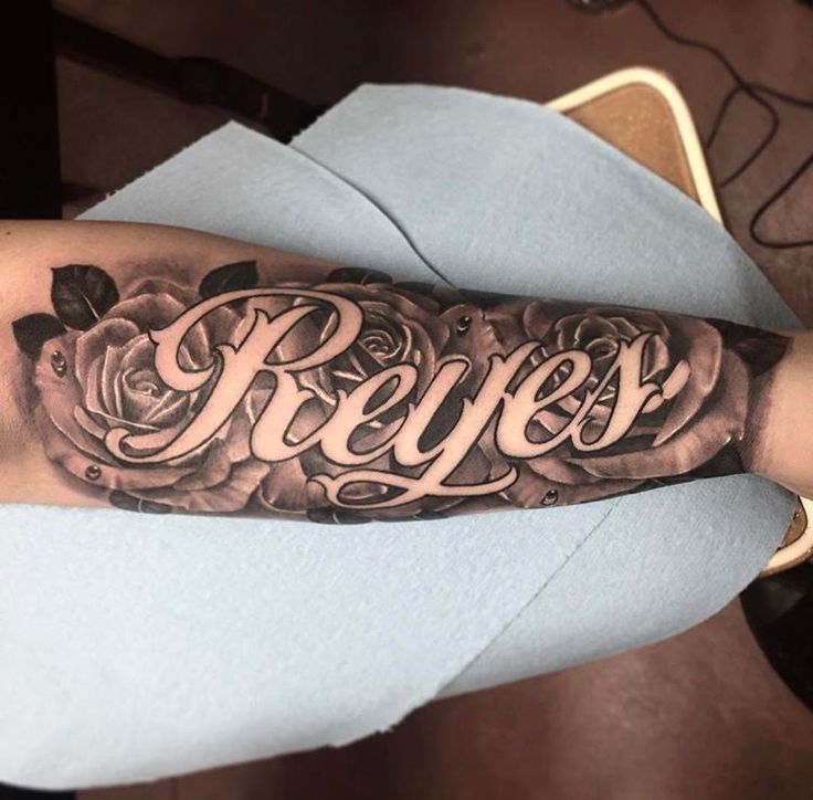 a man's arm with roses and the word reves tattooed on his arm