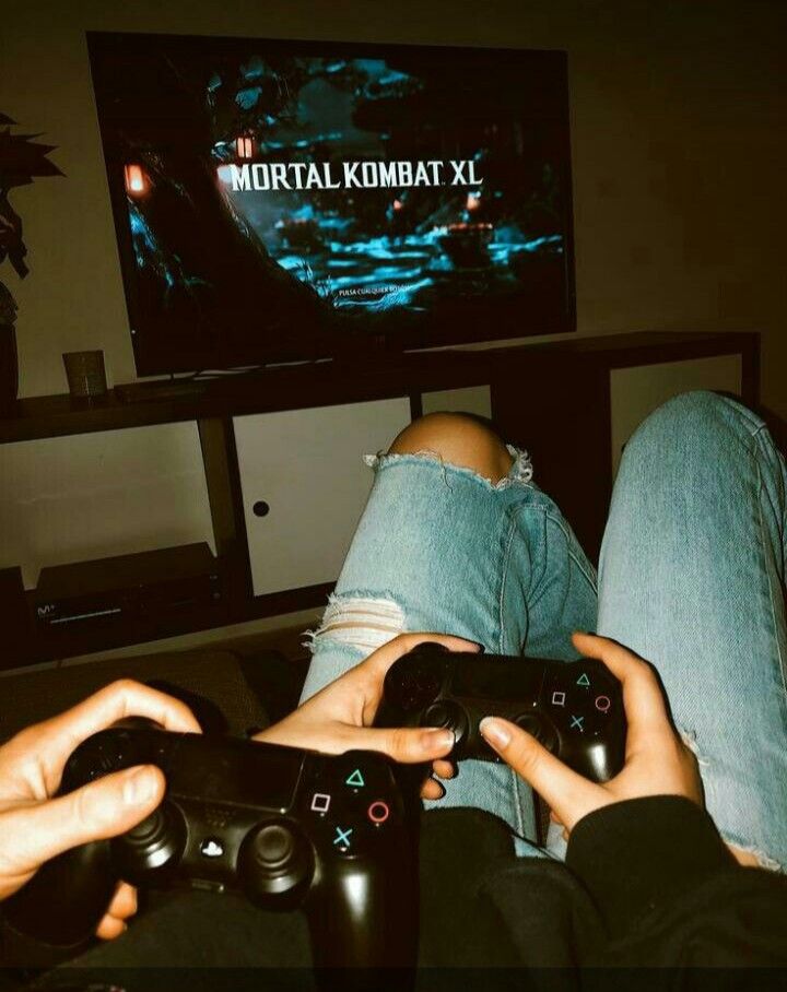 two people are playing video games in front of a tv with their feet on the couch