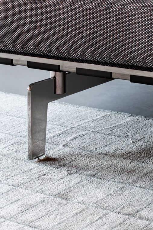 an upholstered bench with metal legs on carpet