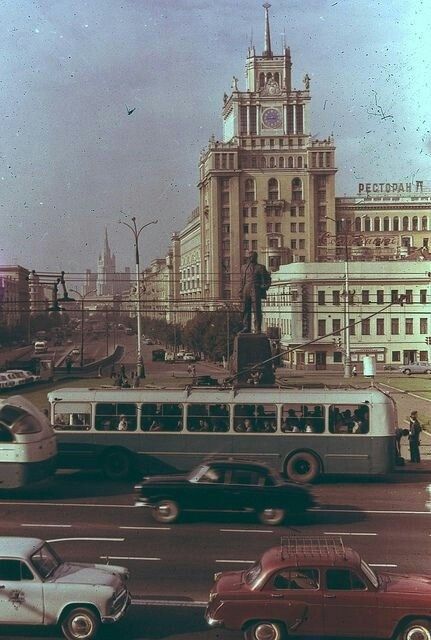 an old photo of cars and buses on a city street with buildings in the background