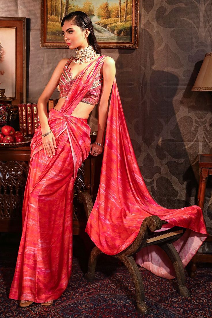 Coral silk satin pre-stitched digitally printed saree. Comes with geometric embroidered cut-out blouse.
Component: 2
Pattern: Print and Embroidery
Type Of Work: Digital print, Geometric embroidery
Neckline: Cut-out
Sleeve Type: Sleeveless
Fabric: Blouse - Dupion, Saree - Silk Satin
Color: Coral
Other Details: 
Geometric embroidery
Cut-out details
Note: The neckpiece worn by the model is not for sale
Occasion: Destination Wedding - Aza Fashions Coral Saree, Draped Saree Gown, Drape Sarees, Embroidery Neckline, Draped Saree, Indian Outfits Lehenga, Coral Blouse, Saree Gown, Saree Silk