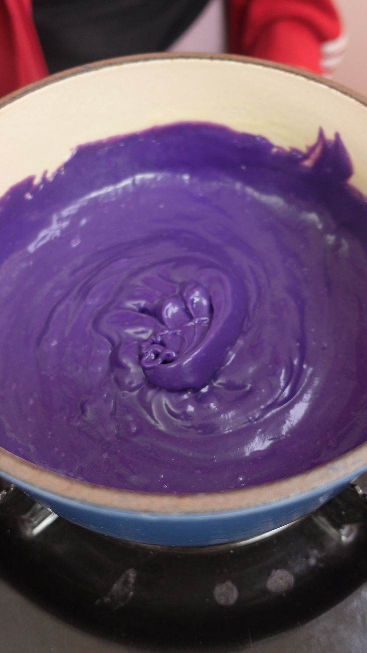 a bowl filled with purple liquid sitting on top of a stove