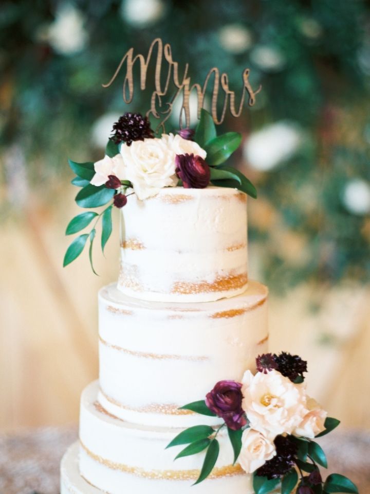 a white wedding cake with flowers and mr and mrs topper on the bottom tier