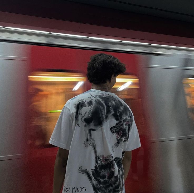 a man standing in front of a train at a station with his back to the camera