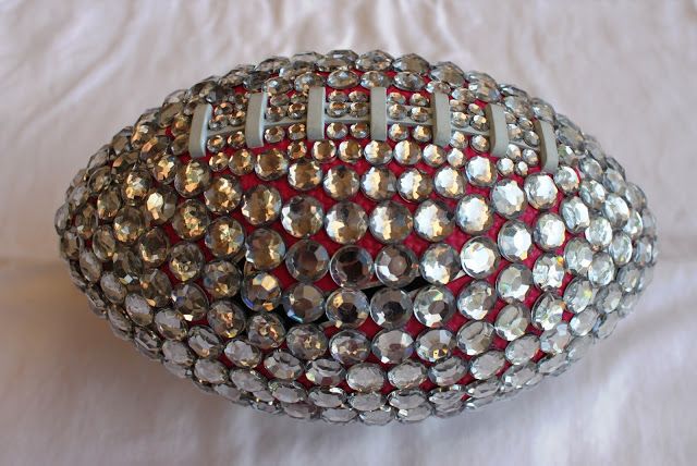 a silver and red football sitting on top of a white bed sheet with the ball covered in crystal stones