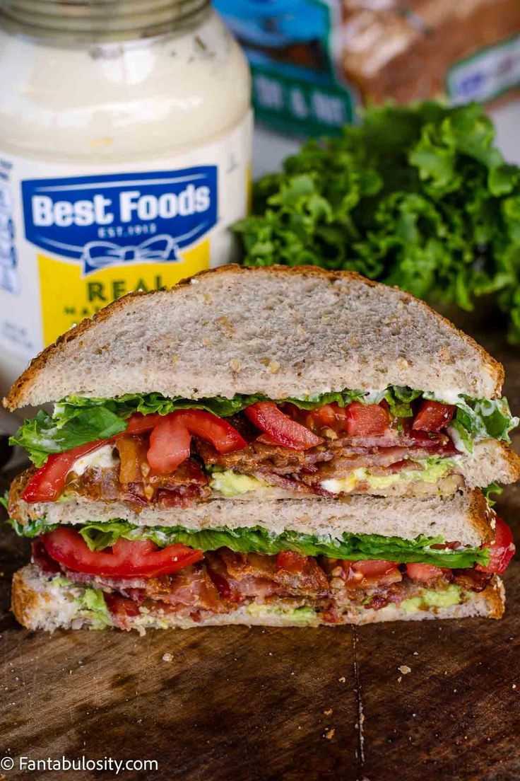 a cut in half sandwich sitting on top of a cutting board next to a jar of mayonnaise