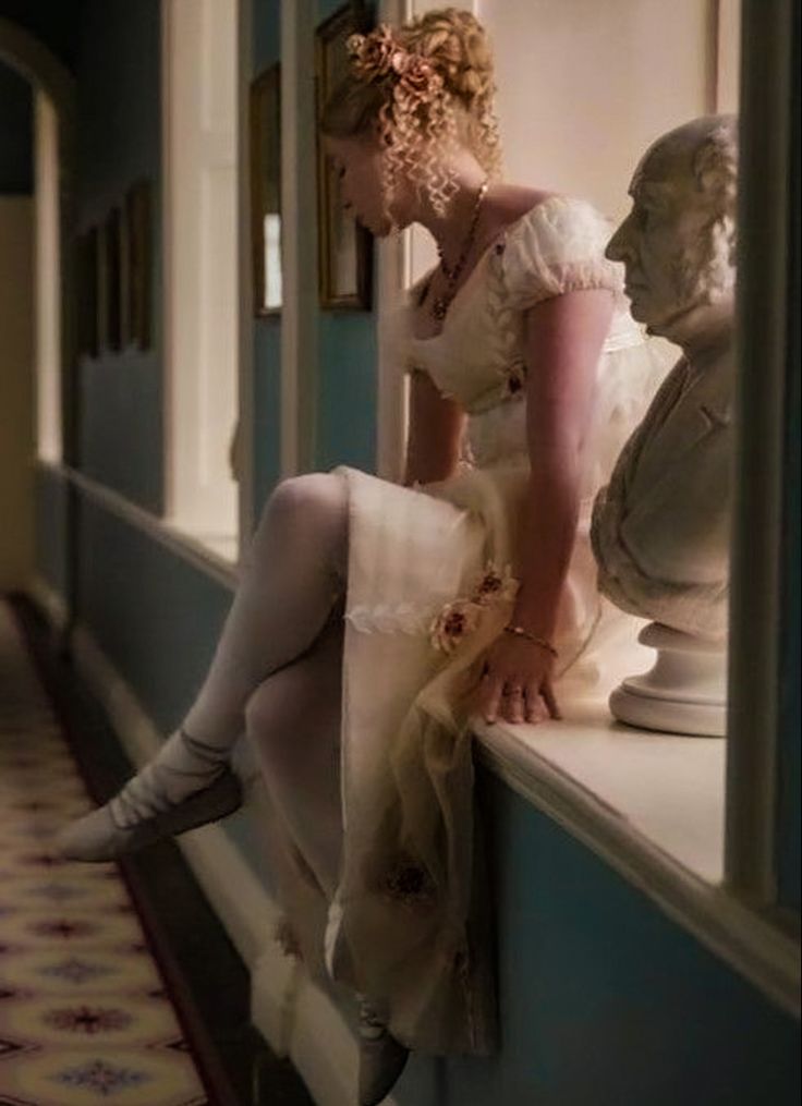 a woman sitting on top of a window sill next to a busturine