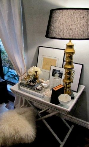 a table with a lamp, pictures and other items on it in front of a window