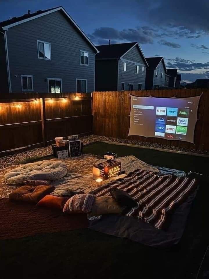 an outdoor movie screen is lit up in the backyard at night with lights on it