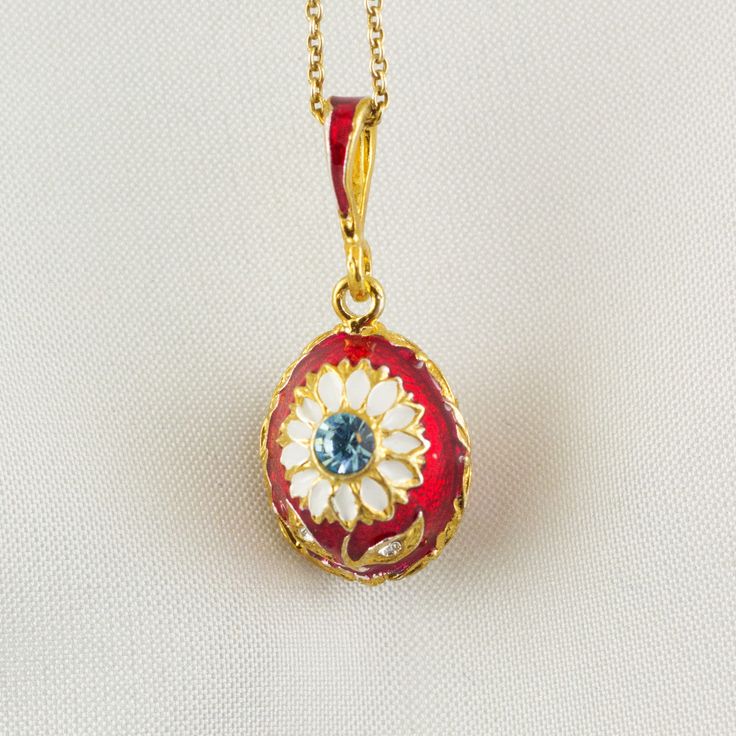 "A small pendant with the daisy flower, enameled and 24 K gold plated over solid sterling silver, created in our NJ shop in the spirit and tradition of Faberge jewelry eggs. The surface of the piece is covered by rich red enamel, underlining a cute white flower with a gentle sky blue Swarovski crystal at the center. Clear Swarovski crystals are set in the leaves. The egg is pretty small - about 0.5\" (14 mm ) long - and will be appropriate for a girl as well as a grown up woman. It comes with 18 Grown Up Woman, Red Flower Necklace, White Daisy Flower, Bouquet Jewelry, Faberge Jewelry, Sterling Silver Charm Necklace, Red Pendant, Sunflower Pendant, Red Pendants