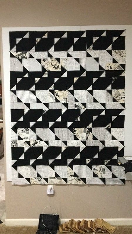 a black and white quilt hanging on the wall next to a pair of shoes in front of it