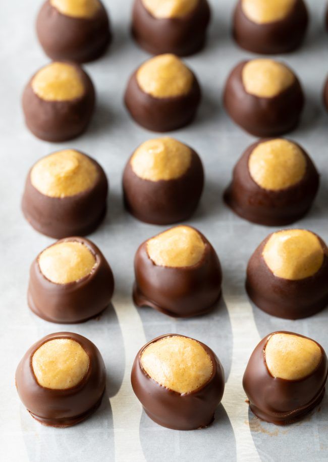 chocolates with yellow frosting are lined up on a baking sheet