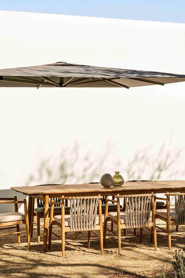 an outdoor dining table and chairs with an umbrella over it